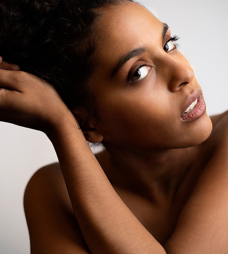 Denver Hydrafacial model in salon attire with curly hair.