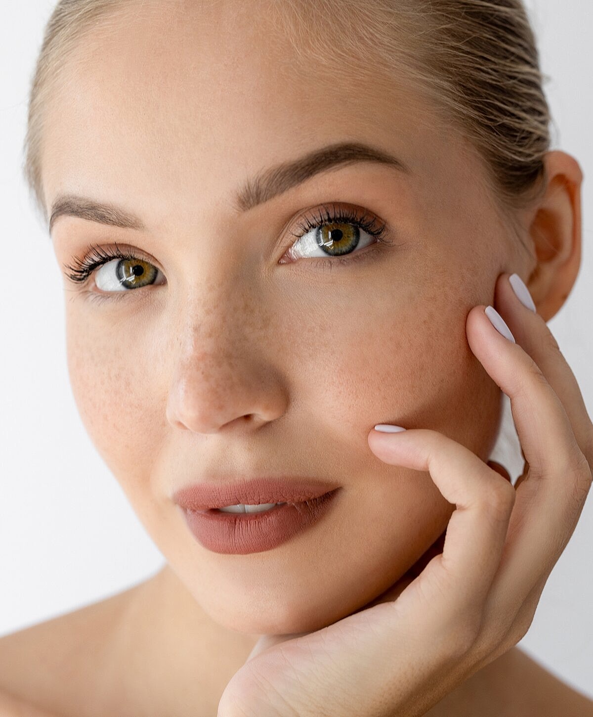 Close-up of woman with freckles and soft makeup.