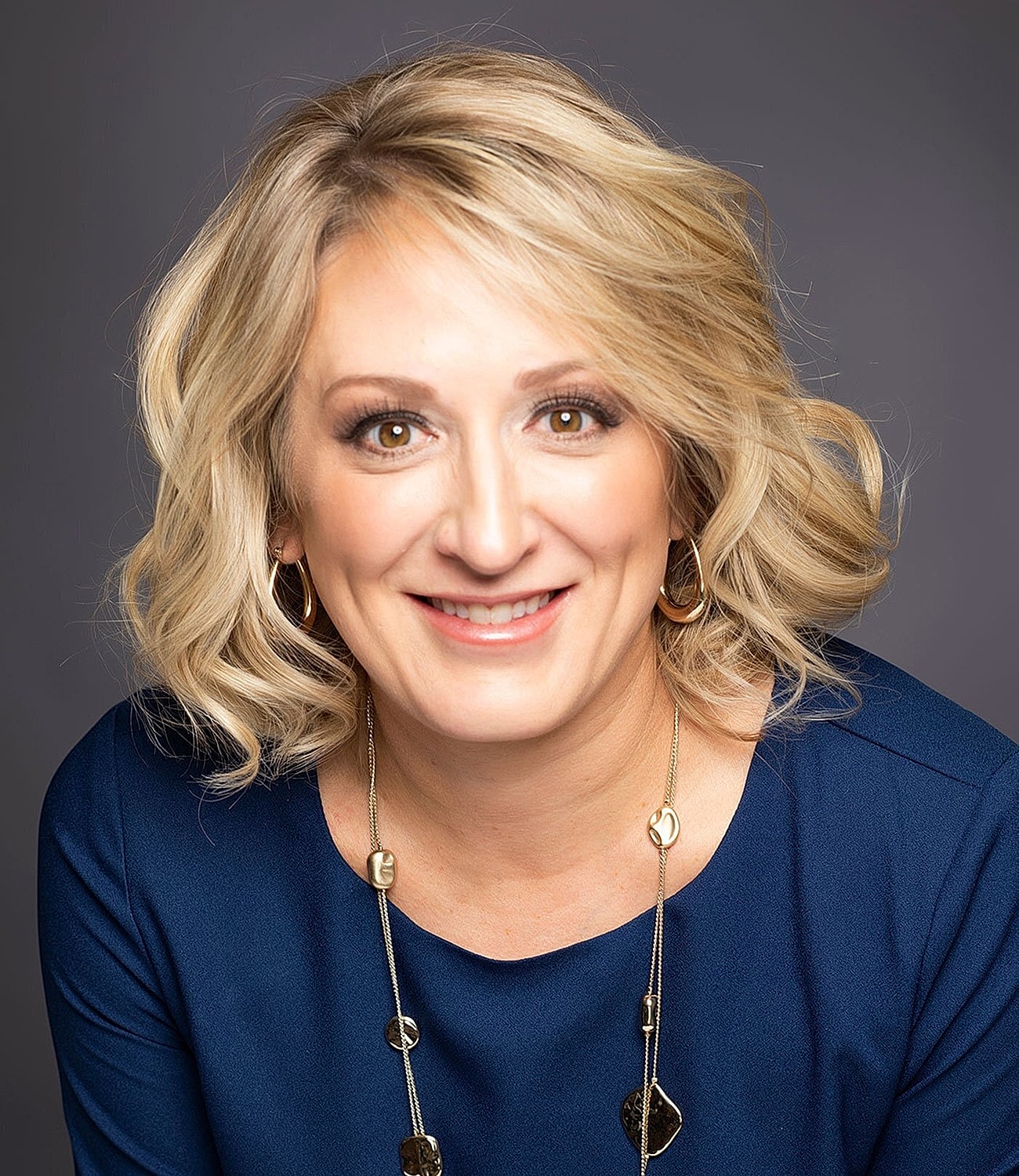 Smiling woman with blonde hair, black shirt.