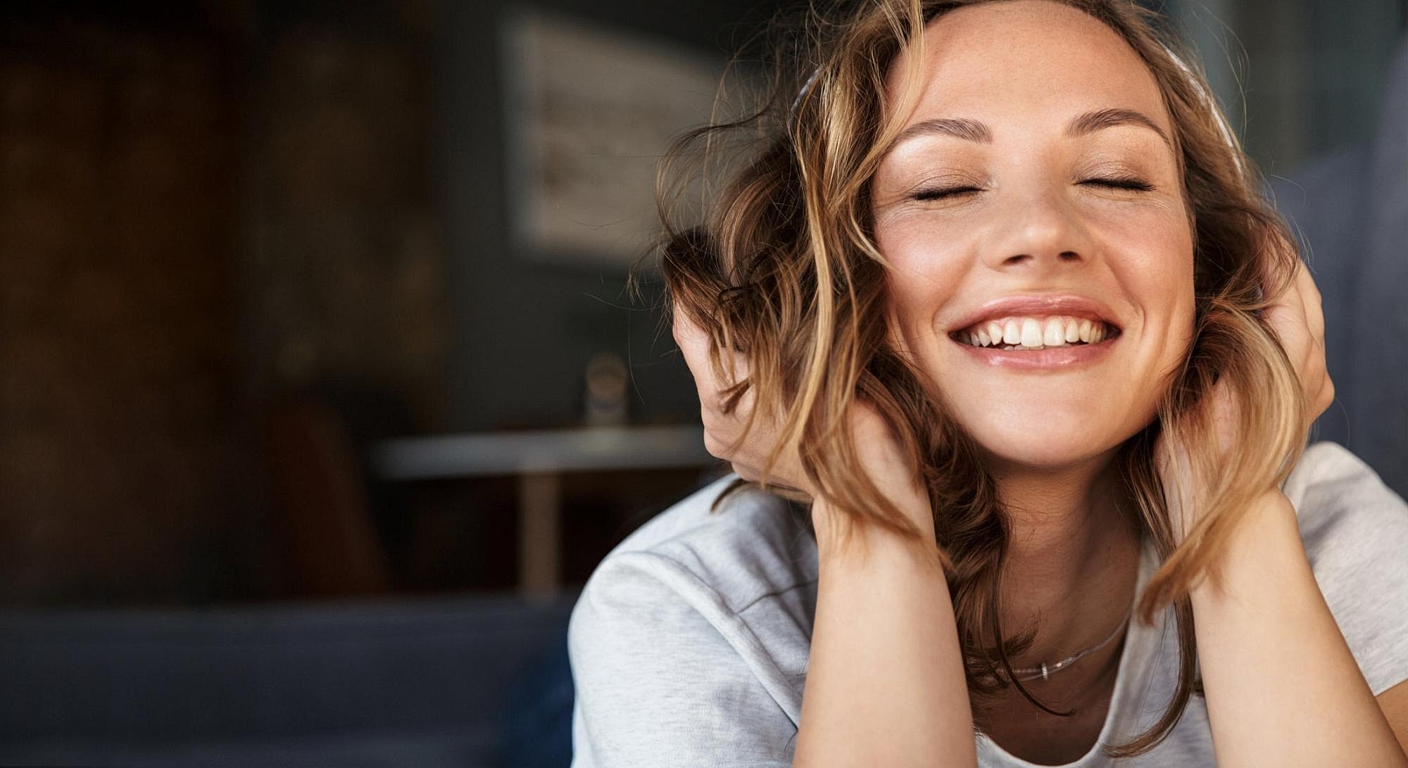 Woman smiling with hands in her hair.