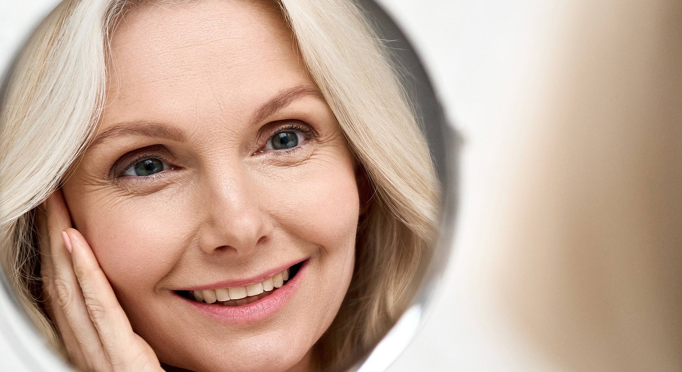 Smiling woman touching her face in mirror.