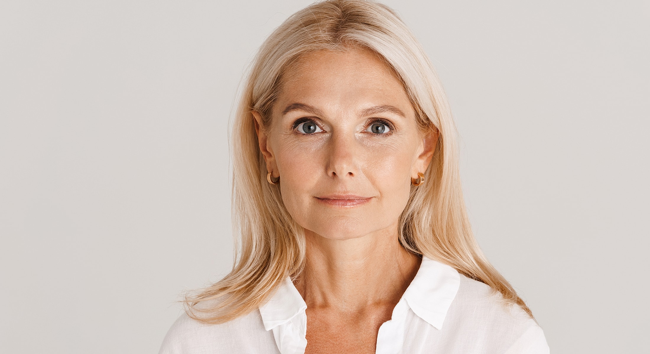 Woman touching her hair, smiling softly at camera.