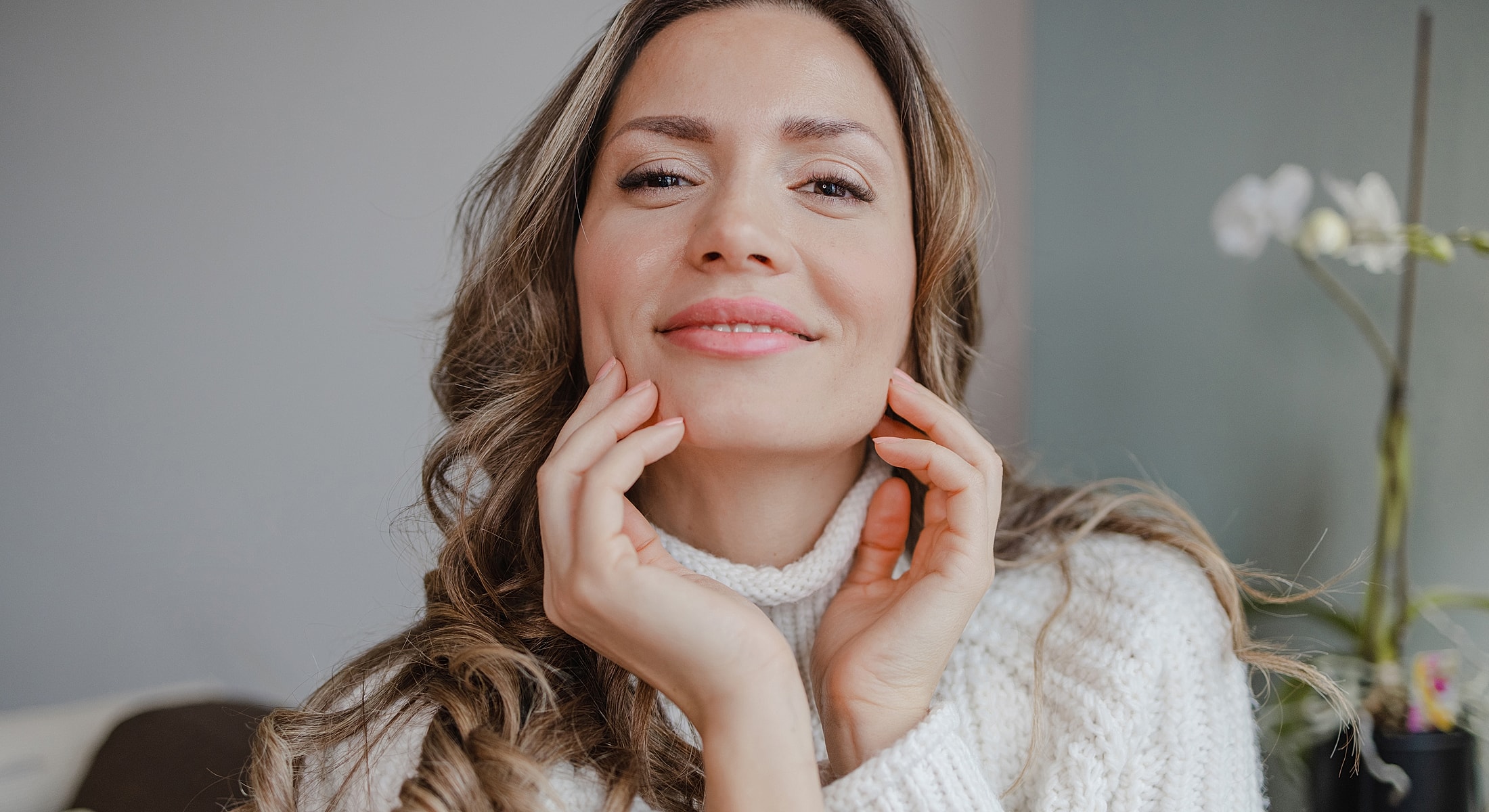 Smiling woman with wavy hair in cozy sweater.
