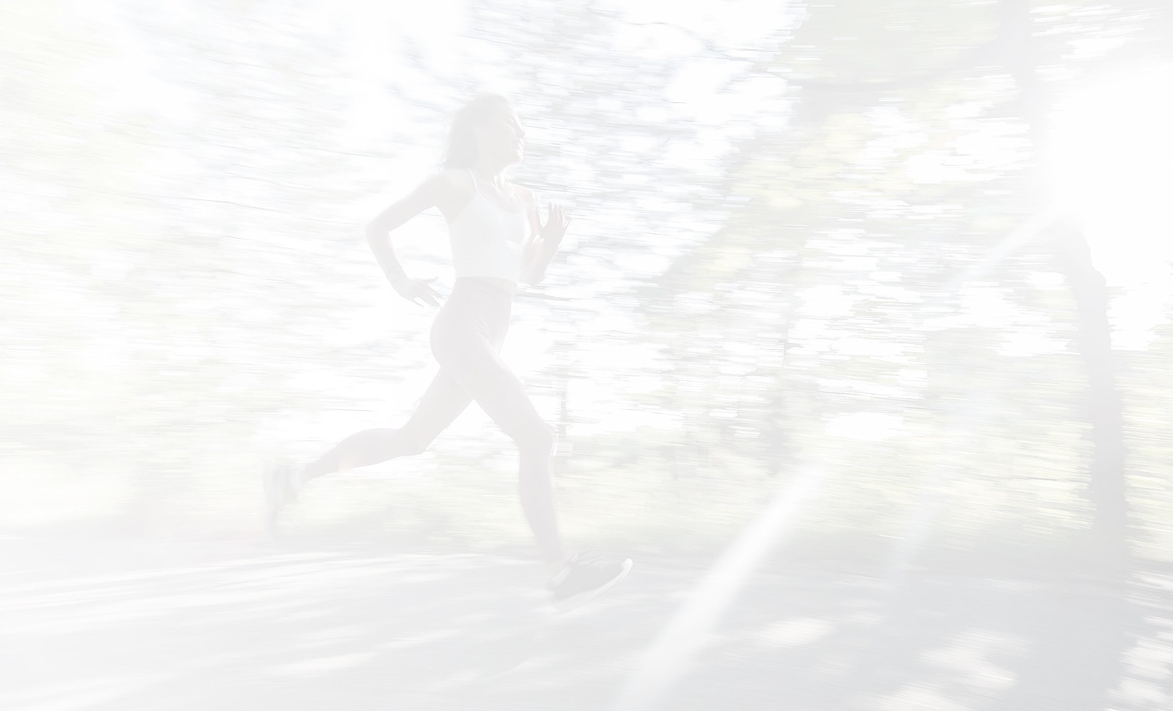 Woman running through a sunlit forest pathway.