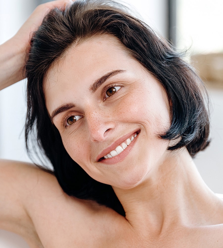 Smiling woman with short, dark hair indoors.