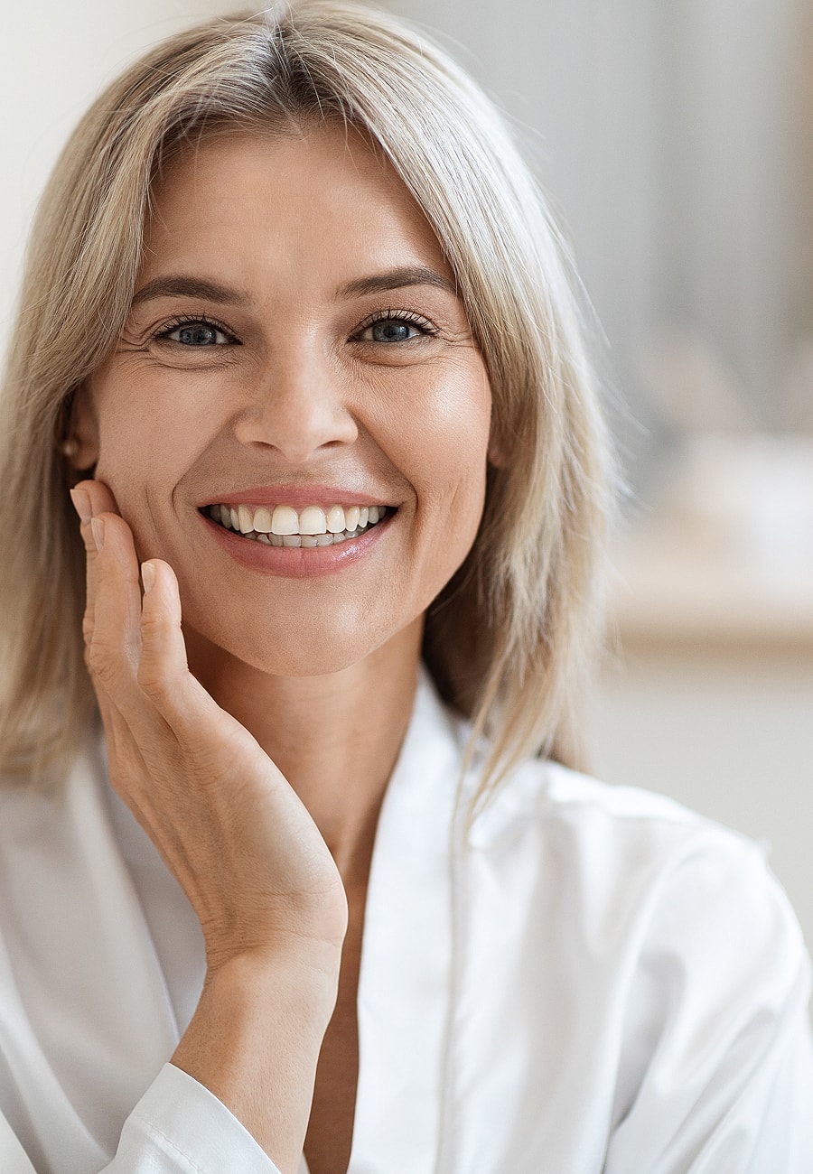 Smiling woman touching her face gently.