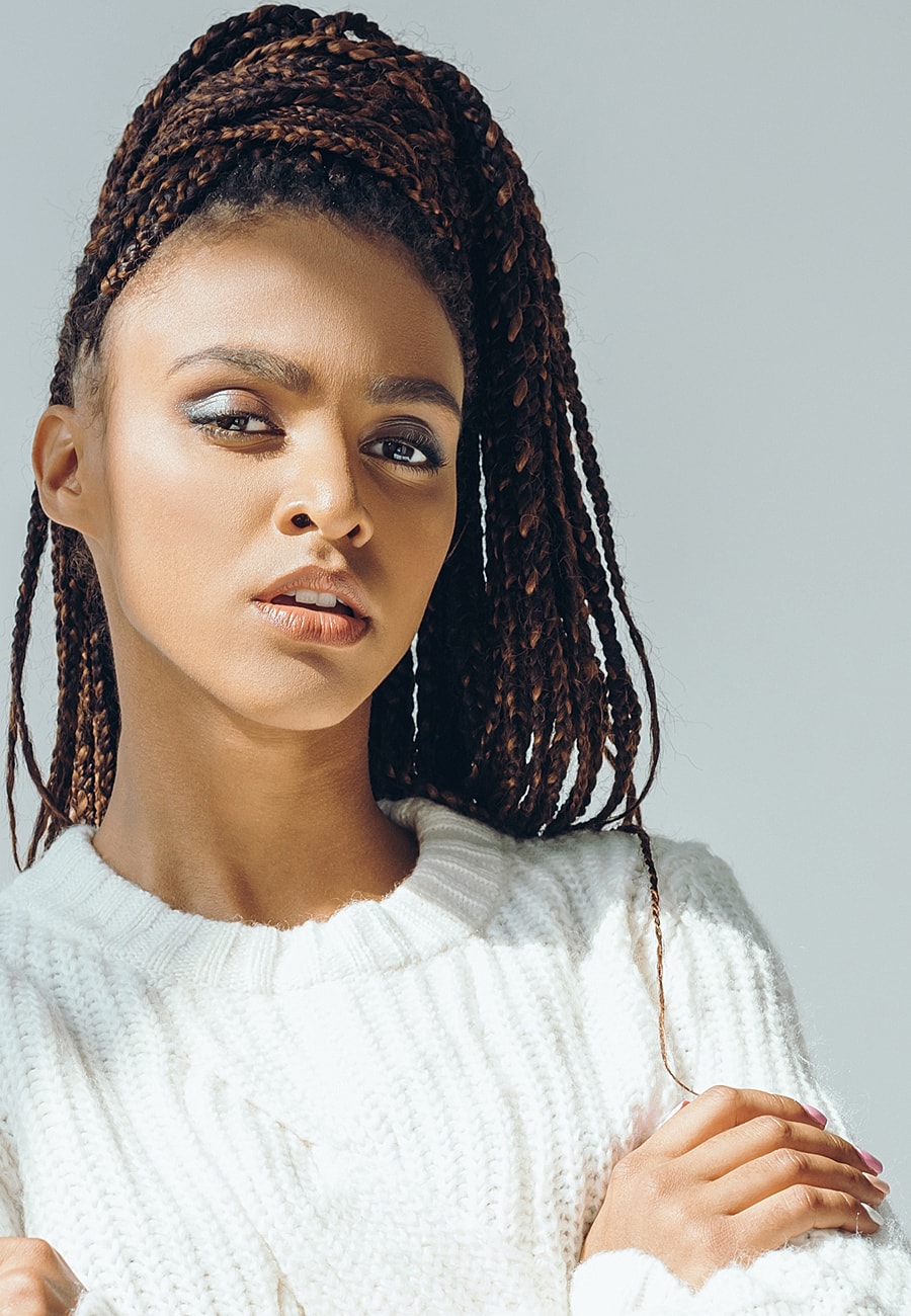 Woman with braided hair in a white sweater.